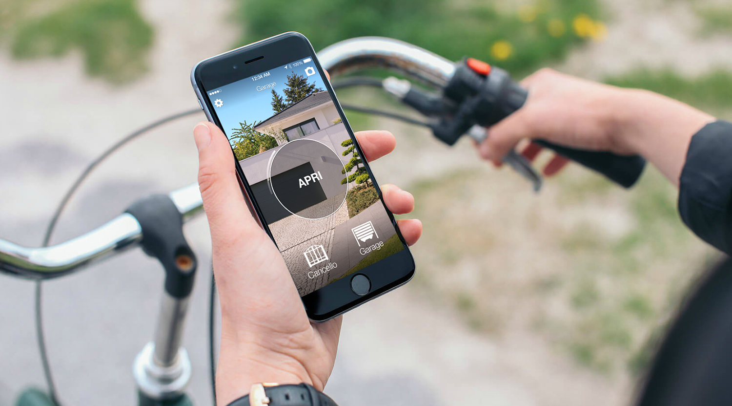 Tor mit Smartphone öffnen: Hand hält Handy mit 1Control App vor dem Einfahrtstor